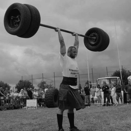2010 UK 105kg2 Paul Wood lifting an axle bar overhead during a strongman competition, showcasing his incredible strength and determination.